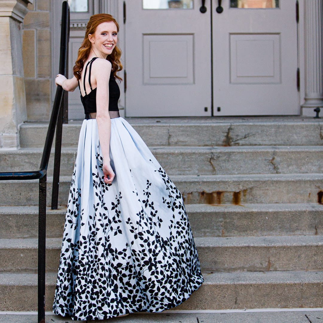 Noblesville Senior High School Student wearing her formal homecoming dress standing in front of the Hamilton County courthouse, leaning against the stair hand rail. Credit: Studio Kate Portrait Design - Noblesville Senior Pictures