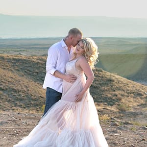 A young couple embraces with the mountains behind them. Photo by Kate Plummer of Studio Kate Portrait Design