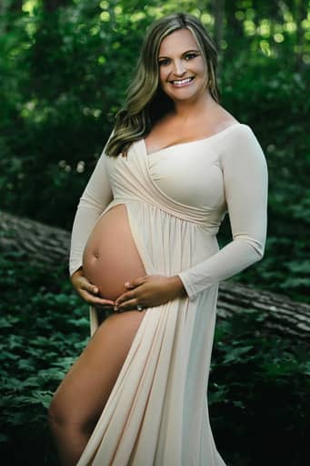 Beautiful pregnant blonde lady in the woods wearing an open-front cream dress that exposes her baby bump. Image courtesy of Noblesville maternity photographer - Studio Kate Portrait Design