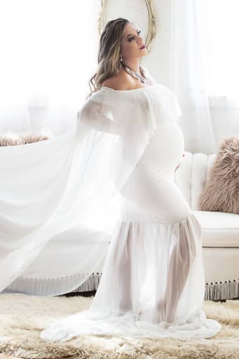 Beautiful pregnant Hispanic lady wearing a white sheer dress that accentuates her baby belly as the light flows through revealing her curves. Maternity pictures courtesy of Noblesville photographer - Studio Kate Portrait Design