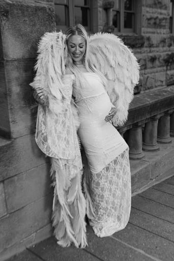 Beautiful maternity photo of a pregnant woman leaning against a decorative concrete bridge wearing a tight white dress and a pair of angel wings. Image courtesy of Noblesville maternity portrait photographer, Studio Kate Portrait Design